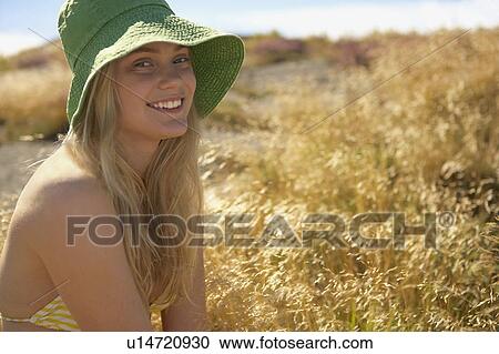 Stock Image - Young Woman Sitting in Long grass.. Fotosearch