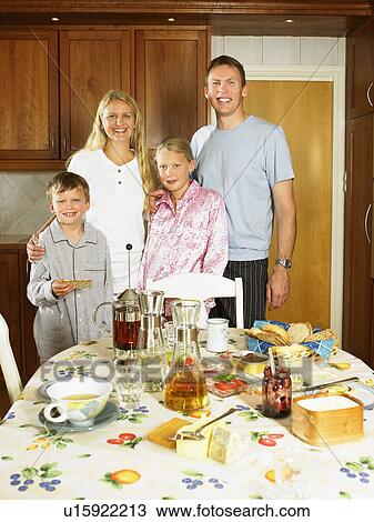 Family standing in kitchen smiling with breakfast on table. View Large Photo Image Stock Image - Family standing in kitchen smiling with breakfast on table.. Fotosearch