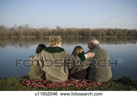 Grandparents, grandson (12-14) and granddaughter (10-12) sitting by river, rear view View Large Photo Image Stock Photograph - Grandparents, grandson (12-14) and granddaughter (10-12) sitting by river, rear view. Fotosearch