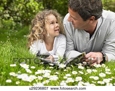 Man and young girl lying in the grass reading and smiling. View Large Photo Image Stock Photo - Man and young girl lying in the grass reading and smiling.. Fotosearch