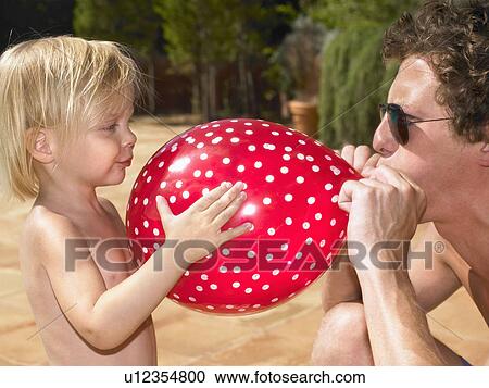 Stock Image - Man blowing up a balloon for a young girl.. Fotosearch