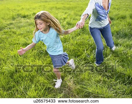 Stock Image - Mother and daughter playing in a field.. Fotosearch