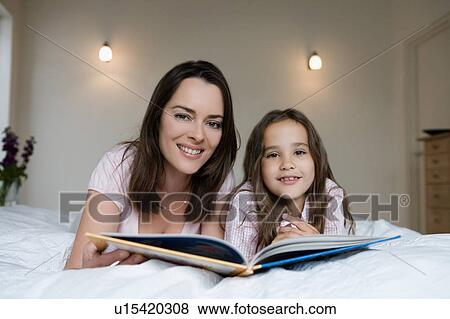 Stock Photo - Mother and daughter sitting on a bed.. Fotosearch