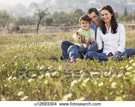 Parents and son (6-8) sitting in field, smiling, portrait View Large Photo Image Picture - Parents and son (6-8) sitting in field, smiling, portrait. Fotosearch