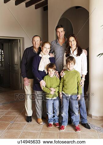 Stock Image - Three generation family standing in hall, smiling, portrait. Fotosearch