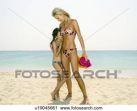 Stock Image - Woman and young girl at the beach smiling.. Fotosearch
