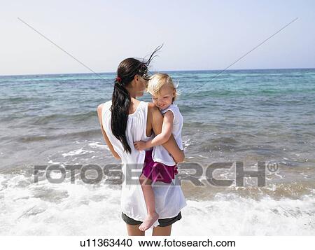 Woman holding a smiling young girl at the beach. View Large Photo Image Stock Image - Woman holding a smiling young girl at the beach.. Fotosearch