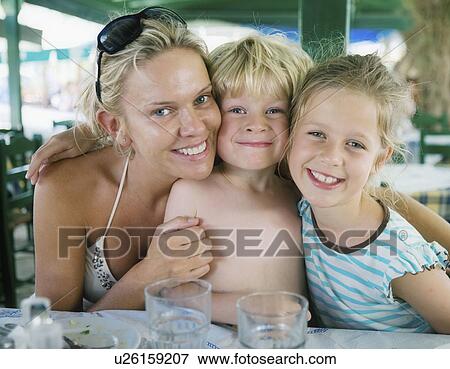 Stock Photo - Woman with young girl and young boy at an outdoor restaurant smiling.. Fotosearch