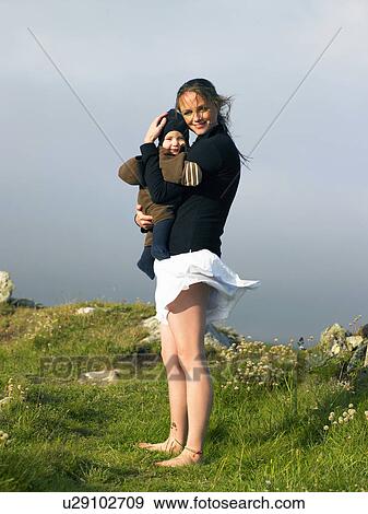 Young woman holding baby with the wind blowing her skirt. View Large Photo Image Stock Photo - Young woman holding baby with the wind blowing her skirt.. Fotosearch