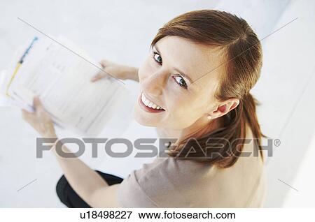 Stock Photo - Happy woman looks up from paperwork. Fotosearch
