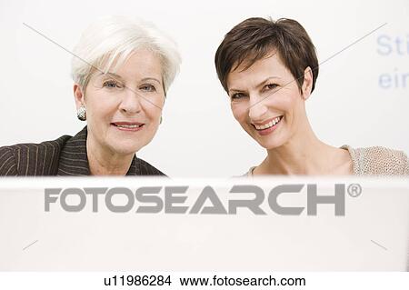 Picture - Two women from the front looking in pc. Fotosearch