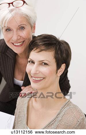 Two women smiling into camera View Large Photo Image Stock Photograph - Two women smiling into camera. Fotosearch