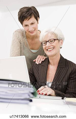 Stock Photograph - Two women working together at a pc. Fotosearch