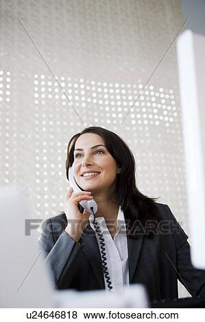 Stock Photo - Woman phoning from office table. Fotosearch