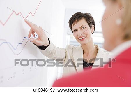 Stock Photo - Woman showing another woman a chart. Fotosearch