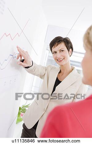 Stock Photograph - Woman showing another woman a chart. Fotosearch