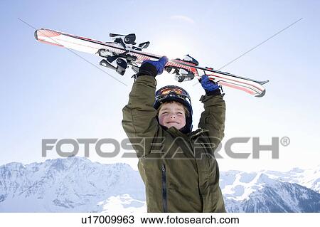 Stock Image - Boy holding skis above his head. Fotosearch