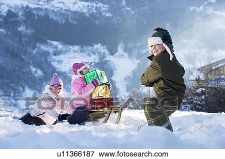 Stock Photo - Children playing in snow with presents. Fotosearch