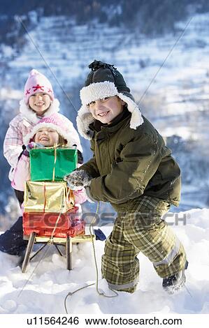 Stock Photograph - Children playing in snow with presents. Fotosearch