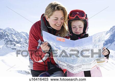 Stock Image - Mother and daughter reading piste map. Fotosearch