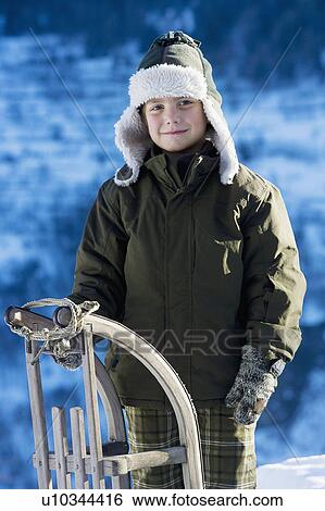 Stock Photograph - Portrait of young boy with sledge. Fotosearch