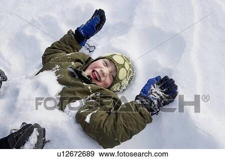 Stock Photo - Young boy lying in snow. Fotosearch