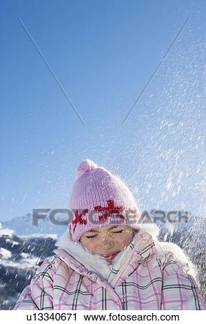 Stock Image - Young girl with snow falling on her. Fotosearch