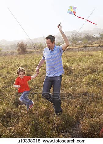 Father and son (4-6) running in field with kite, smiling View Large Photo Image Stock Photo - Father and son (4-6) running in field with kite, smiling. Fotosearch