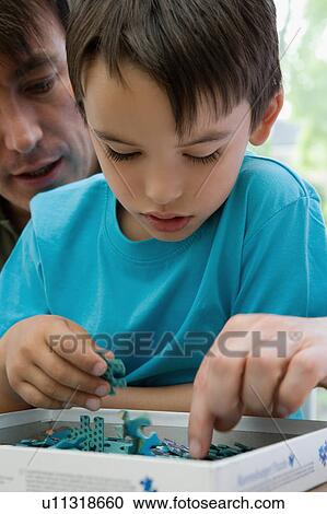 Stock Image - Father and son doing a jigsaw puzzle.. Fotosearch