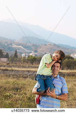 Father carrying son (6-8) in field, smiling, portrait View Large Photo Image Stock Image - Father carrying son (6-8) in field, smiling, portrait. Fotosearch