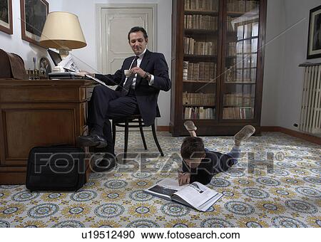 Father sitting at desk and son (4-6) reading book View Large Photo Image Stock Image - Father sitting at desk and son (4-6) reading book. Fotosearch