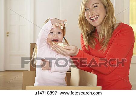 Stock Photo - Girl (3-5) playing in box with mother smiling, portrait. Fotosearch