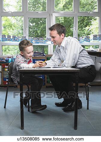 Male teacher helping young boy with work in classroom View Large Photo Image Stock Photography - Male teacher helping young boy with work in classroom. Fotosearch