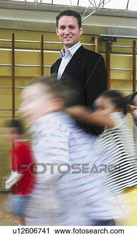 Stock Image - Male teacher standing in gymnasium.. Fotosearch