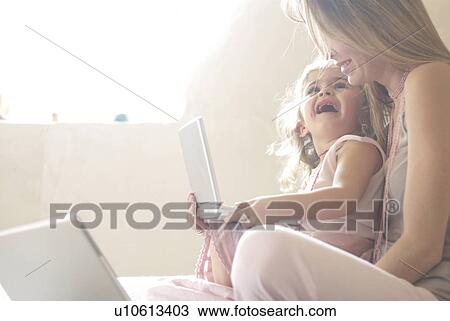 Stock Image - Mother and daughter (2-4) using laptop.. Fotosearch
