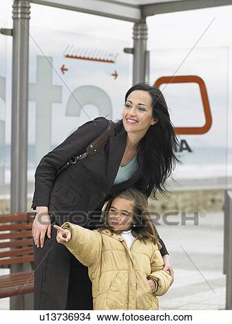 Picture - Mother and daughter (6-8) waiting at tram, girl pointing. Fotosearch