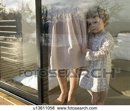 Stock Photo - Mother and daughter (9-12 months) looking through window.. Fotosearch