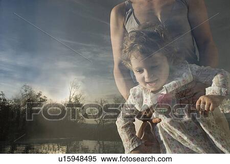 Stock Photography - Mother and daughter (9-12 months) looking through window.. Fotosearch