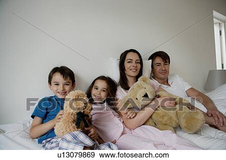 Portrait of a family sitting on a bed. View Large Photo Image Stock Photo - Portrait of a family sitting on a bed.. Fotosearch