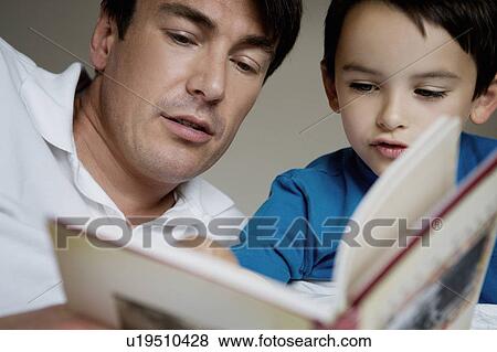Stock Photo - Portrait of a father and son reading.. Fotosearch
