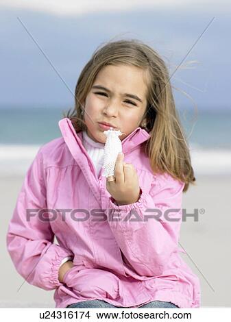 Girl (6-8) sitting on beach raising bandaged finger, portrait View Large Photo Image Picture - Girl (6-8) sitting on beach raising bandaged finger, portrait. Fotosearch