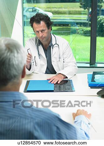Male doctor at his desk talking with mature male patient. View Large Photo Image Stock Image - Male doctor at his desk talking with mature male patient.. Fotosearch