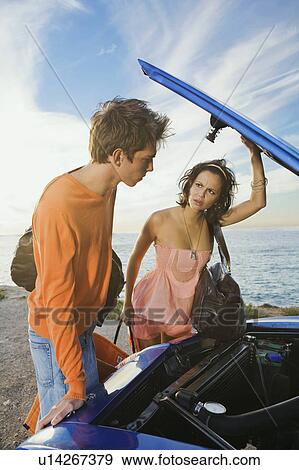 Stock Photo - Man and woman looking under car bonnet.. Fotosearch