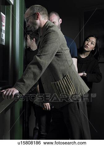 Stock Photograph - Man at counter, woman checking time in queue in background. Fotosearch
