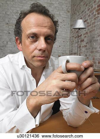 Pensive businessman looking at camera holding coffee cup., Brussels, Belgium. View Large Photo Image Stock Photograph - Pensive businessman looking at camera holding coffee cup., Brussels, Belgium.. Fotosearch
