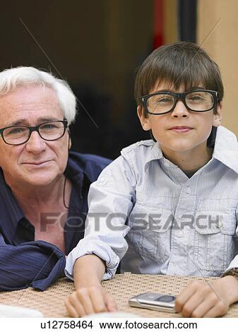 Boy (8-10) and grandfather sitting at café table, wearing black-rimmed spectacles View Large Photo Image Picture - Boy (8-10) and grandfather sitting at café table, wearing black-rimmed spectacles. Fotosearch