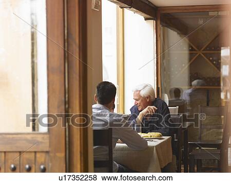Boy (8-10) sitting at café table with father and grandfather View Large Photo Image Stock Photo - Boy (8-10) sitting at café table with father and grandfather. Fotosearch