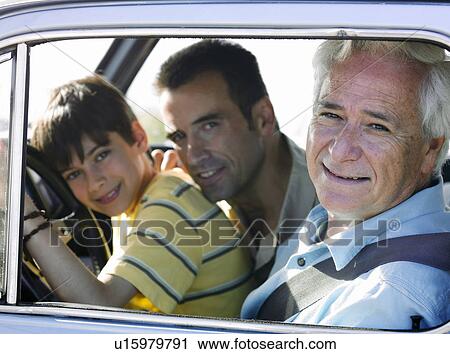 Stock Image - Boy (8-10) sitting in car with father and grandfather, smiling, side view, portrait. Fotosearch
