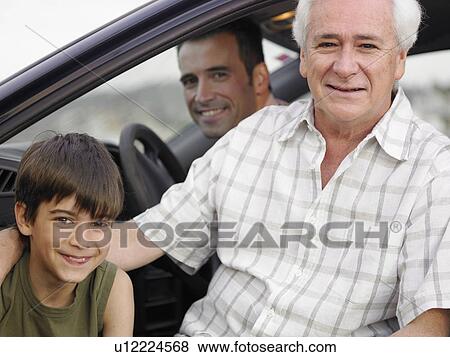 Stock Photo - Boy (8-10) sitting with father and grandfather in parked car, smiling, portrait. Fotosearch