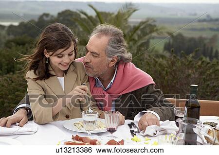 Girl (9-11) sitting with grandfather at a table outside View Large Photo Image Stock Photograph - Girl (9-11) sitting with grandfather at a table outside. Fotosearch
